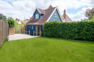 una casa azul con un patio verde en Foxes Lodge en Aldringham