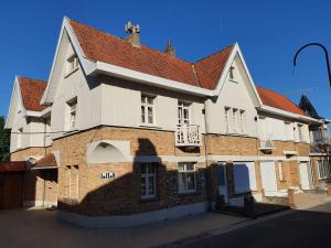 a large brick building with a red roof at Maison au calme à 300m de la plage in De Panne