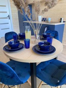 a table with blue chairs and blue dishes on it at Domki Rozewie Holliday in Rozewie