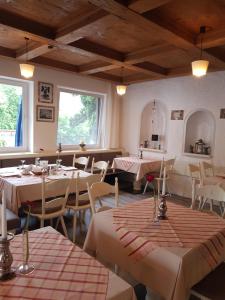 a restaurant with white tables and chairs and windows at Pension – Restaurant Jägerwinkl in Rettenberg