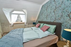 Schlafzimmer mit einem Bett mit blauer Bettwäsche und einem Fenster in der Unterkunft Ferienwohnungen Eifelstuben mit Charme - am See, nahe Burg in Ulmen