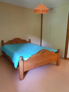 - une chambre dotée d'un lit en bois avec une feuille bleue dans l'établissement Gîte du Moulin, à Les Planches-près-Arbois