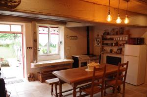 a kitchen with a wooden table and a refrigerator at Chambres d'hôtes du Ruisseau d'Argent in Archettes