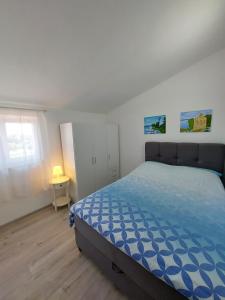 a bedroom with a bed with a blue comforter at Apartman Ana in Štinjan