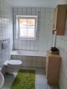 La salle de bains est pourvue de toilettes, d'un lavabo et d'une fenêtre. dans l'établissement Apartment/Ferienwohnung im ruhigen Calden in der nähe von Kassel, à Calden