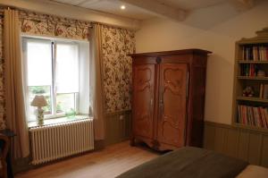 Chambres d'hôtes du Ruisseau d'Argent في Archettes: غرفة نوم مع خزانة خشبية كبيرة ونافذة