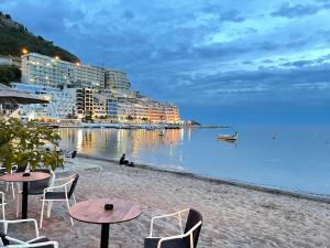 una spiaggia con tavoli, sedie, edifici e l'acqua di Front Row Sunset a Rafailovici