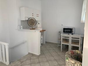 a white kitchen with a table and a fan at villa of the god in Skala