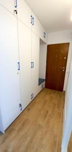 Pokój z białymi szafkami i drewnianą podłogą w obiekcie Apartament Kurka w Hajnówce