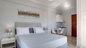 a white bedroom with a white bed and a kitchen at Azure Mare Studios in Corfu