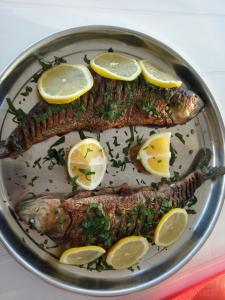 two pieces of fish on a plate with lemon slices at Camping Danubius Tulcea in Tulcea