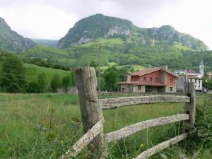 a wooden fence in a field with mountains in the background at Hotel Rural El Fondón in Soto De Agues