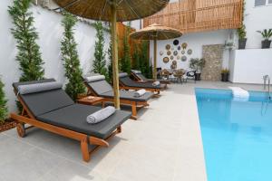 a pool with chaise lounge chairs and an umbrella at Versa Villas in Preveza