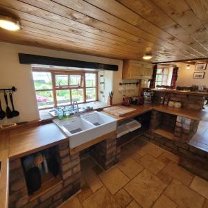 a large kitchen with a sink and wooden ceilings at Loch Lomond shore Boat House in Balmaha