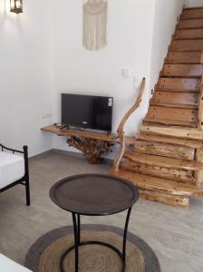 a living room with a tv and a table and stairs at Orange Garden Loft in Kala Nera