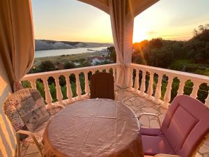 stół i krzesła na balkonie z widokiem na zachód słońca w obiekcie Apartments Stella-Dora w mieście Lopar