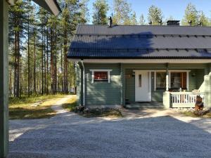 a green house with a white door and a driveway at Villa Wästä-Räkki in Luosto