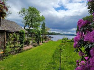a path next to a house next to a body of water at Loch Lomond shore Boat House in Balmaha +17 photos