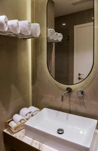 a bathroom with a sink and a mirror and towels at L-Suites in Kavála +59 photos