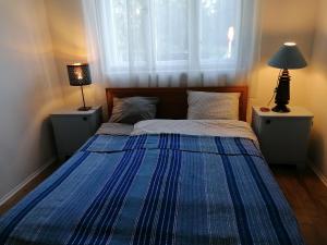 a bedroom with a bed with a blue comforter and a window at Country home @ the Danube Bend in Nagymaros