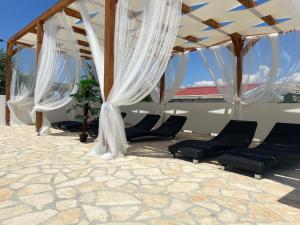 a pavilion with chairs and curtains on a patio at Oguic apartman in Pag