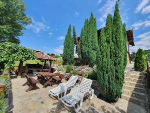 a patio with white chairs and a table and trees at Holiday Home Drinsko svitanje in Gornja Trešnjica