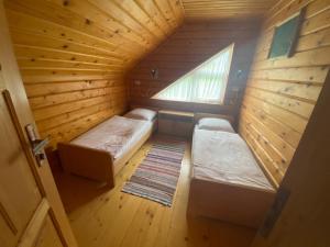 Habitación pequeña con 2 camas en una cabaña de madera en Sadyba Sukhar, en Kolochava