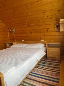 1 dormitorio con 1 cama en una habitación de madera en Sadyba Sukhar, en Kolochava