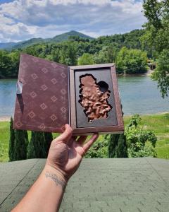 a person holding up a book with a picture on it at Holiday Home Drinsko svitanje in Gornja Trešnjica