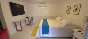 a bedroom with a bed and a desk and a television at Pousada Mestre Augusto in Angra dos Reis