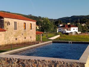 una piscina frente a un edificio de piedra en Casa da Quinta do Cruzeiro, en Fontoura
