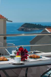una mesa con tazas y platos de comida en el balcón en Apartment Tonka, en Cavtat