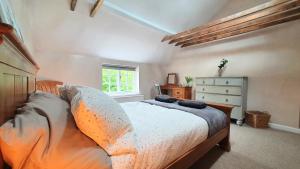 a bedroom with a bed and a dresser and a window at Glenfield Cottage - Secluded Luxury deep in the Oxfordshire Countryside in Wilcote