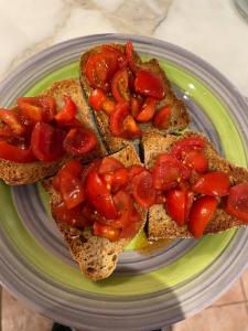 a plate with two slices of bread with tomatoes on it at Tuscan Skye - Caterina Studio Apartment in Barga