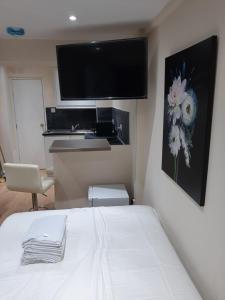 - une chambre avec un lit et une télévision murale dans l'établissement Budget Ensuite Room in Thamesmead, à Londres