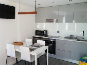 a kitchen with a white table and white chairs at Chalet Pôr do Sol in Castro Daire