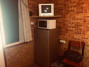 a microwave on top of a refrigerator next to a brick wall at Бунгало- Bungalow in Kavarna