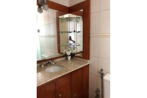 uma casa de banho com um lavatório e um espelho em MRG - Ensolarado 2D - Centro de Gramado em Gramado