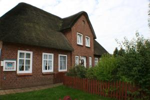 a red brick house with a black roof at Ferienwohnungen im Hotel garni zur Post in Utersum