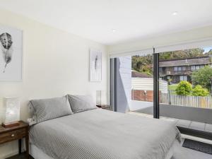 a bedroom with a bed and a large window at One 36 in Lorne