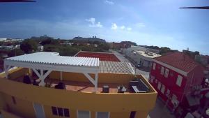 a yellow building with a white roof in a city at Mustique Suites Curacao in Willemstad