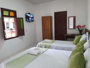 a room with three beds and a tv on the wall at Aconchego Sertanejo in Caetité