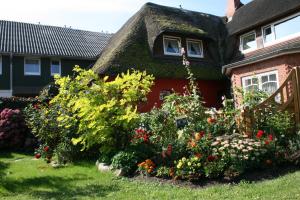 a garden in front of a house with flowers at Ferienwohnungen im Hotel garni zur Post in Utersum