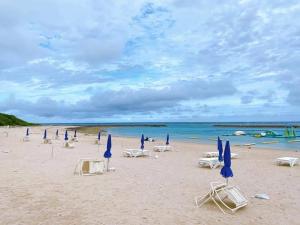 a beach with chairs and umbrellas and the ocean at CH Maezato in Ishigaki Island