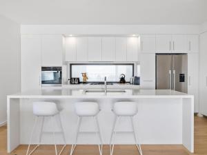 a kitchen with white cabinets and white bar stools at Oceania 1 in Lorne