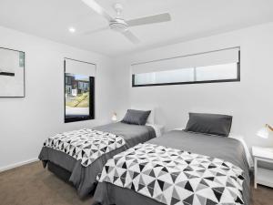 2 Betten in einem Zimmer mit weißen Wänden und Fenstern in der Unterkunft Oceania 1 in Lorne