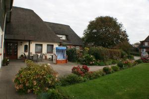 a house with a patio and a yard with flowers at Ferienwohnungen im Hotel garni zur Post in Utersum