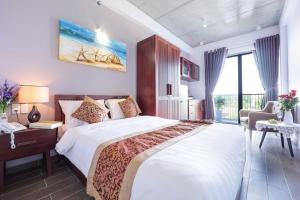 a bedroom with a large white bed and a window at The Shine Hotel & Apartment in Da Nang