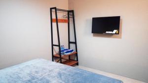 Habitación con cama y TV en la pared. en Hostel 18 Pasangan Butuh Surat Nikah en Bandung