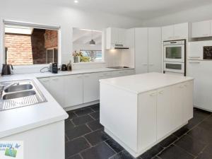 a white kitchen with white cabinets and a sink at Eight Lakes in Merimbula
